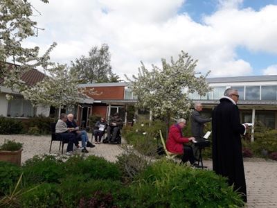 præst og beboere i haven på Solgården