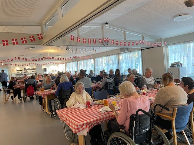 Tarteletfest. Beboere, pårørende og personale i cafeen ved smukt pyntede borde